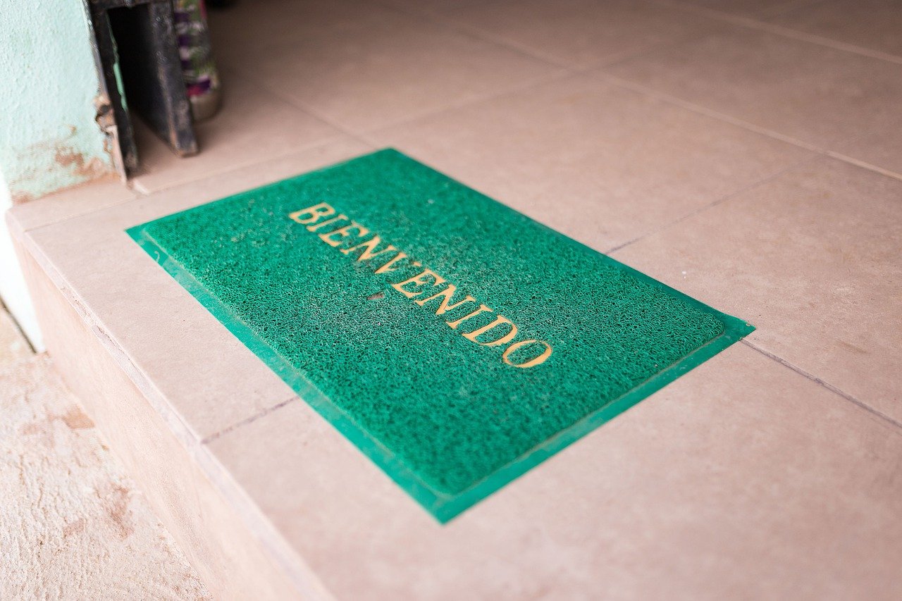 Green door mat with welcome printed on it placed on tiled floor